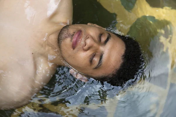 Portrait of Hispanic man floating in a natural pool with eyes closed- man relaxing in hot springs in Guatemala