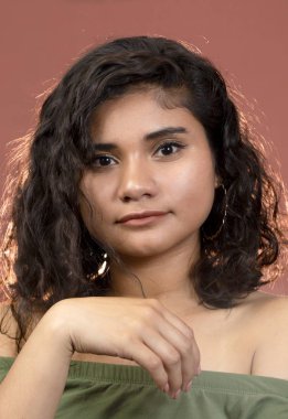 Kıvırcık saçlı esmer, çıplak omuzlu Latin bir kız kameraya bakıp gülümsüyor. Latin bir kadın.