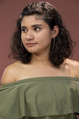 Kıvırcık saçlı esmer, çıplak omuzlu Latin bir kız kameraya bakıp gülümsüyor. Latin bir kadın.