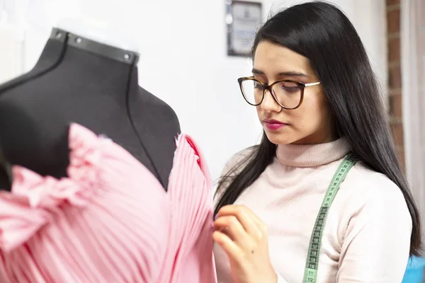 Stüdyodaki İspanyol moda tasarımcısı tasarımları üzerinde çalışıyor ölçüler alıyor ve girişimci bir kadını ayarlıyor.