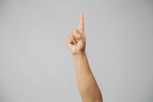 Мужская рука с номером один, указательный палец в студии на сером фоне — стоковое фото