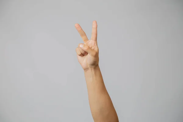 Männerhand mit Nummer zwei, Hand hebt zwei Finger Zeigefinger in die Höhe im Studio mit grauem Hintergrund, Symbol der Liebe und des Friedens — Stockfoto