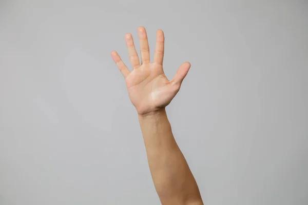 Mano dell'uomo con il numero cinque, mano alzando tutte le dita in studio con sfondo grigio ... — Foto Stock