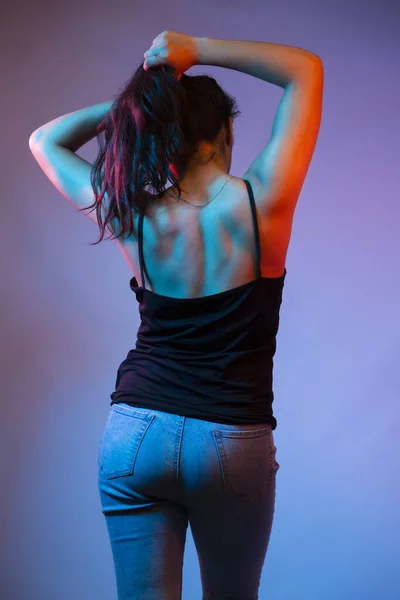 Kvinnans rygg med tonade och tränade muskler med neonfärgade lampor - sexig kvinna i studio med färgade ljus — Stockfoto