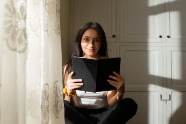 Genç İspanyol bir kadın kitap okuyor, ciddi bir kız gün batımında odasında siyah bir kitap izliyor. Yoğunlaşmış genç bayan evde çalışıyor..