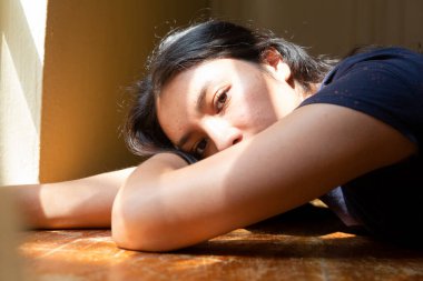 Kollarında güneş ışığı olan bir masada uzanmış İspanyol genç bir kadın. Genç bir kadın. Güneşin tadını çıkartıyor, üzgün ve ciddi bir kadın..