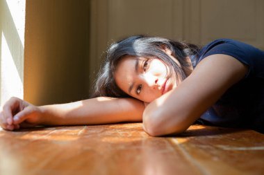 Kollarında güneş ışığı olan bir masada uzanmış İspanyol genç bir kadın. Genç bir kadın. Güneşin tadını çıkartıyor, üzgün ve ciddi bir kadın..