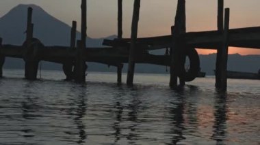 atitlan göl rıhtımında gün batımı, volkan arka planıyla, gün batımında kırsal iskelede güzel bir göl manzarası.