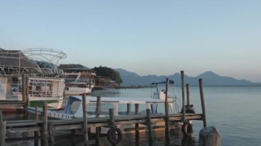 Atitlan göl rıhtımında gün batımı, tekne arka planında, gün batımında kırsal iskelede güzel bir göl manzarası.