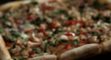 Yakın plan İtalyan pizzası, sebzeli, ev yapımı yemek tarifi, gurme, pizza mutfakta taze malzemelerle çevrili, ahşap bir masa üzerinde.