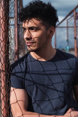 Metal bir örgü önünde genç İspanyol bir adamın portresi öğleden sonra güneşiyle - çatıda günbatımını izleyen genç adam - şehir tarzı