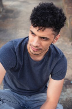 Bulutlu bir öğleden sonra çatıda oturan düşünceli genç bir İspanyol 'un portresi.