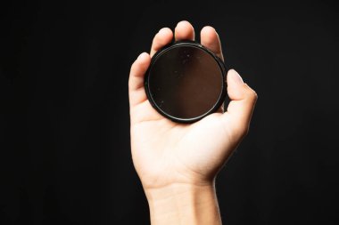 Siyah arka planda küçük dairesel bir ayna tutan genç bir kadının eli - stüdyo fotoğrafçılığı