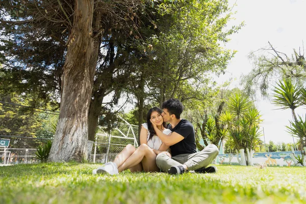 Pareja Joven Hispana Enamorada Sentada Hierba Abrazándose Divirtiéndose Pareja Paseando —  Fotos de Stock