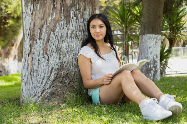 Spaanse Jongeman Zit Onder Een Boom Het Park Lezen Een — Stockfoto