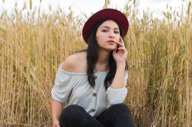 Bulutlu bir öğleden sonra, altın buğday tarlasında genç bir İspanyol kadın. Doğanın ortasında bir tarlada hippi kız.