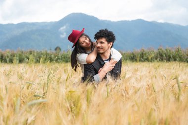 Birbirlerine aşık bir çift buğday tarlasında eğleniyor mutlu, genç, İspanyol bir çift, yaz tatilinin tadını çıkarırken kız arkadaşını sırtında taşıyor.