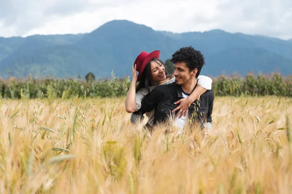 Birbirlerine aşık bir çift buğday tarlasında eğleniyor mutlu, genç, İspanyol bir çift, yaz tatilinin tadını çıkarırken kız arkadaşını sırtında taşıyor.