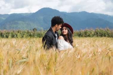 Buğday tarlasının ortasında kucaklaşan genç İspanyol çift, altın buğday tarlasında aşk anının tadını çıkarıyor.
