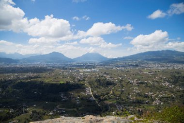 Güneşli bir günde, ağaçlarla, dağlarla ve volkanla çevrili, Quetzaltenango Guatemala 'daki manzarayla çevrili, dağın tepesinden görünen küçük bir kasabanın güzel manzarası..