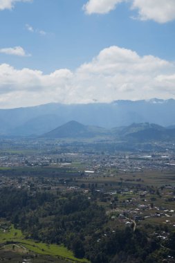 Güneşli bir günde, ağaçlarla, dağlarla ve volkanla çevrili, Quetzaltenango Guatemala 'daki manzarayla çevrili, dağın tepesinden görünen küçük bir kasabanın güzel manzarası..