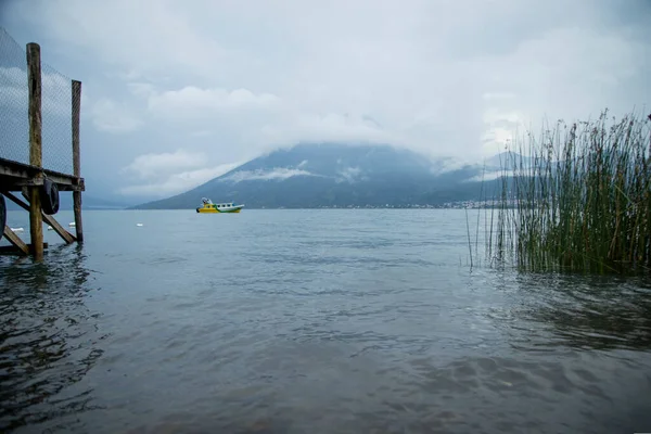 Landscape of a beautiful lake with a yellow boat in the middle on a cloudy day - winter day on the lake with beautiful trees and vegetation on the shore