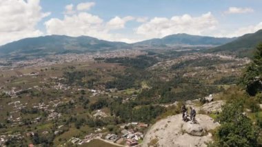 Dağın tepesindeki bir grup arkadaş önlerindeki kasabaların manzarasını takdir ediyor. Uçurumun kenarındaki arkadaşlar Quetzaltenango Guatemala 'da eğleniyorlar.