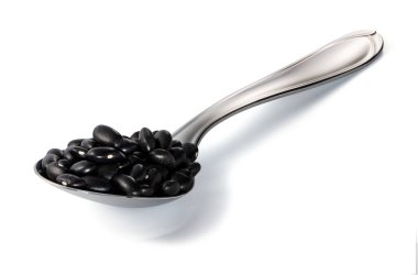 Çelik kaşıkta siyah fasulye kepçesi Beyaz arka planda kırpma yolu ile izole edildi