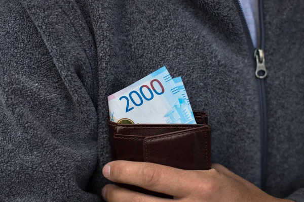 New Russian Banknotes Of 2000 Thousands Rubles In Leather Purse In Hands Of Male On Background Of Gray Fleece Jacket Close Up.