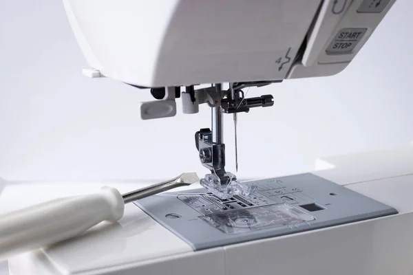 Sewing Machine Repair. White Sewing Machine With Tool Of Screwdriver Close Up.