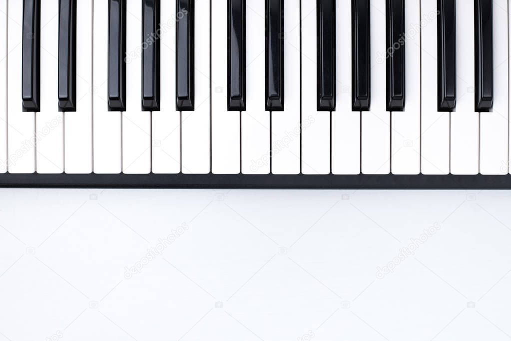 Black And White Piano Keys On White Background Of Wooden Table In Musical Studio Top View.