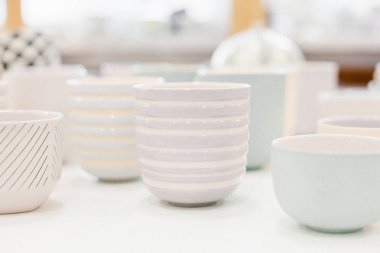 Yumuşak arkaplanda çok renkli seramik minimalist vazo ve fincanlar.