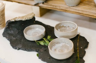 Masanın üzerinde küçük gri seramik tabaklar var..