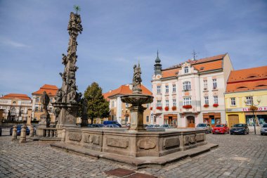Kutsal Üçlü Sütun, Aziz Florian heykeli ve tarihi binaların bulunduğu tarihi bir çeşme güneşli bir günde, Kuzey Bohemya, Çek Cumhuriyeti, 19 Eylül 2020