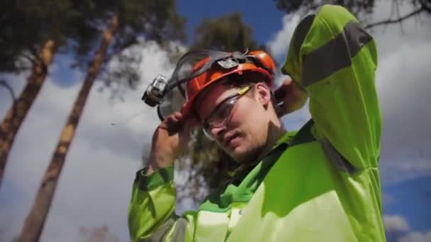Boomkweker draagt een beschermende helm en bril — Stockvideo