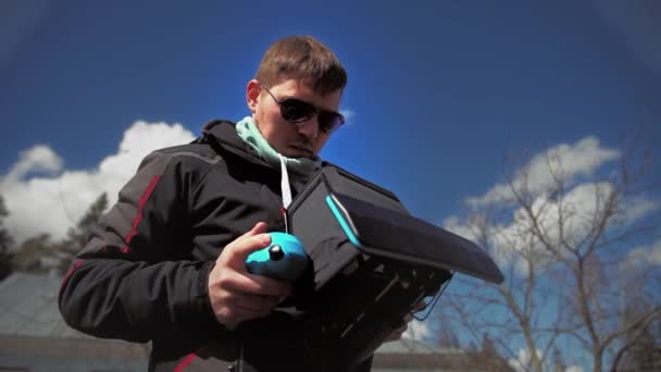 Hombre con gafas de sol controla el dron y lo mira — Vídeo de stock