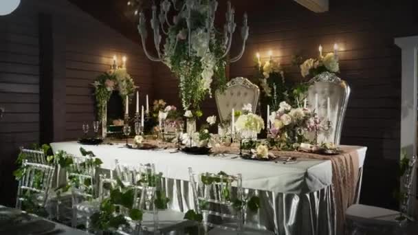 A table set with black arrows with food, wine glasses, flower vases, candlesticks with candles behind which stands two thrones — Stock Video