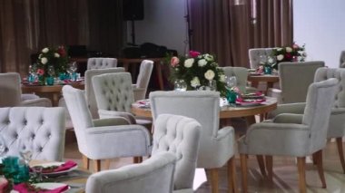 yuvarlak ahşap masa olan yumuşak sandalye pembe peçete ile beyaz tabak yapılmış çiçek düzenlemeleri ile dekore edilmiş