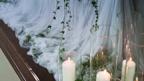 Het presidium van de pasgetrouwden versierd met een bloemstuk, met kaarsen in een vaas en een boog, disco lichten werken — Stockvideo