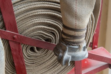 Eski bir gri yangın hortumu özel stand ahşap bir duvara bağlı yanmaz malzemeden yapılmış. Metalden yapılmış borular bağlanma.