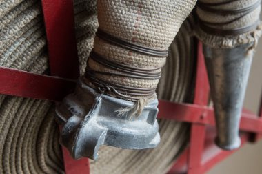 Eski bir gri yangın hortumu özel stand ahşap bir duvara bağlı yanmaz malzemeden yapılmış. Metalden yapılmış borular bağlanma.