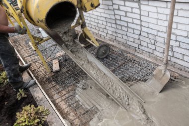 Manuel modda bir konut kırsal evin etrafında bir beton kaldırım inşaatı. El ile pişmiş harç beton karıştırıcı. Özel bir araç ile kaldırım yüzey tesviye