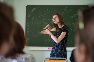 St. Petersburg, Rusya - 10 Haziran 2018: Üniversitede genç bir öğretmen öğrencilere İspanyolca'nın fonetiklerini anlatıyor, jestler yapıyor ve tahtada açıkça gösteriyor..