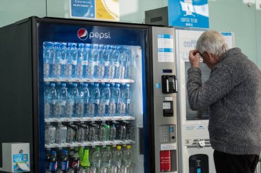 St. Petersburg, Rusya Federasyonu - 8 Ekim 2018: yaşlı bir adam havaalanında bir meşrubat makinesi teklerse seçer. Bekleme odasında depo donatımı.