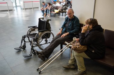 St. Petersburg, Rusya - 8 Ekim 2018: hasarlı bacağından havaalanının yanında yatılı için sağlanan bir tekerlekli sandalye ile yaşlı bir adam. Uçuş bekliyor. Kendi koltuk değneği.