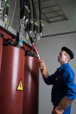 St. Petersburg, Rusya Federasyonu - 19 Nisan 2016: Elektrikçi uzman bir yüksek gerilim trafo bakım çalışmaları yürütmektedir. Uzun sonda topraklama telleri giderir.