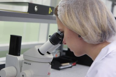 St. Petersburg, Rusya Federasyonu - 29 Kasım 2010: Optogan tesisi modern Led superbright aydınlatma donanımları, bir kız laboratuvar asistanı mikroskop çalışır