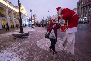 St. Petersburg, Rusya Federasyonu - 9 Aralık 2018: Noel Baba stilts Nevsky Prospect boyunca yürür. Geçenler eğlendirir. Bir bavul elinde. Xmas