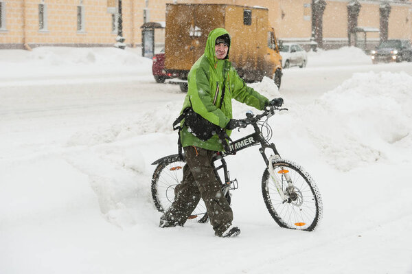 St. Petersburg, Russia - November 8, 2016: Young positive man on a sports bike in winter clothes against the background of snow machines.