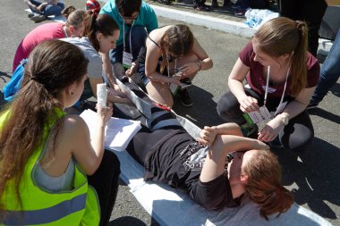 St. Petersburg, Rusya Federasyonu - 12 Mayıs 2018: yarışma / egzersizleri ilk yardım öncesi hastane aşamada. Katılımcıların bir grup bir bıçak-kesik bacak yaralanma alınan bir kız yardımcı olur..